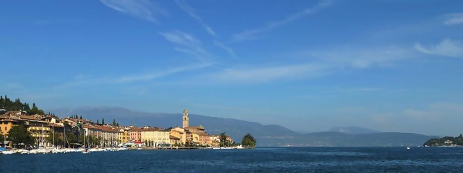Trip Griechenland beliebte Urlaubsziele am Gardasee -  Mit einer Fläche von 370 km² ist der Gardasee der größte See Italiens. Es liegt am Fuße der Alpen und erstreckt sich über drei Staaten: Lombardei, Venetien und Trentino. Die maximale Tiefe des Sees beträgt 346 m, er hat eine längliche Form und sein nördliches Ende ist sehr schmal. Dort ist der See von den Bergen der Gruppo di Baldo umgeben. Du trittst aus deinem gemütlichen Hotelzimmer und es begrüßt dich die warme italienische Sonne. Du blickst auf den atemberaubenden Gardasee, der in zahlreichen Blautönen schimmert - von tiefem Dunkelblau bis zu funkelndem Türkis. Majestätische Berge umgeben dich, während die Brise sanft deine Haut streichelt und der Duft von blühenden Zitronenbäumen deine Nase kitzelt. Du schlenderst die malerischen, engen Gassen entlang, vorbei an farbenfrohen, blumengeschmückten Häusern. Vereinzelt unterbricht das fröhliche Lachen der Einheimischen die friedvolle Stille. Du fühlst dich wie in einem Traum, der nicht enden will. Jeder Schritt führt dich zu neuen Entdeckungen und Abenteuern. Du probierst die köstliche italienische Küche mit ihren frischen Zutaten und verführerischen Aromen. Die Sonne geht langsam unter und taucht den Himmel in ein leuchtendes Orange-rot - ein spektakulärer Anblick.